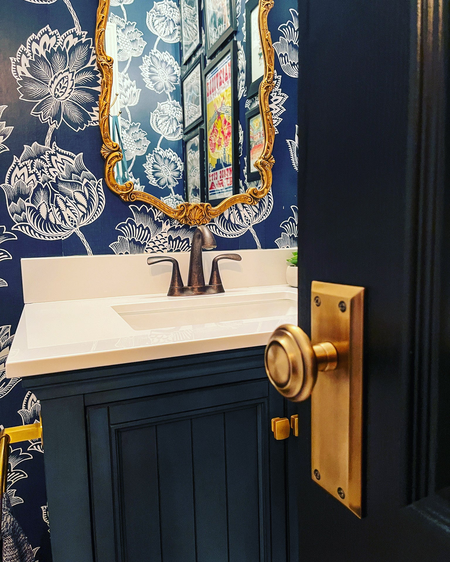 Door opening into a blue themed bathroom with blue flowered wallpaper.