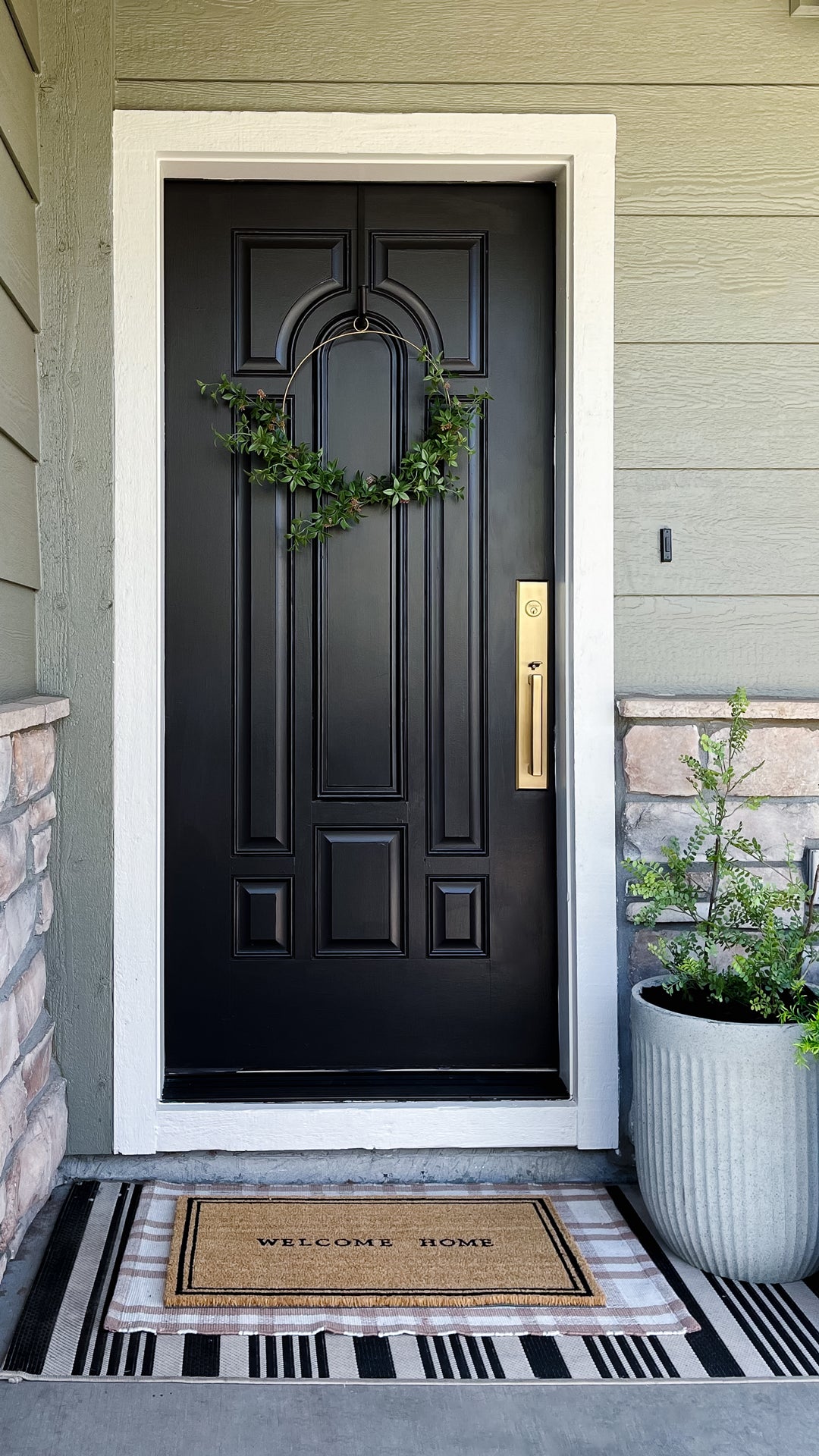 Black front door with Grandeur Fifth Avenue One-Piece Handleset with D Grip in Vintage Brass on it.