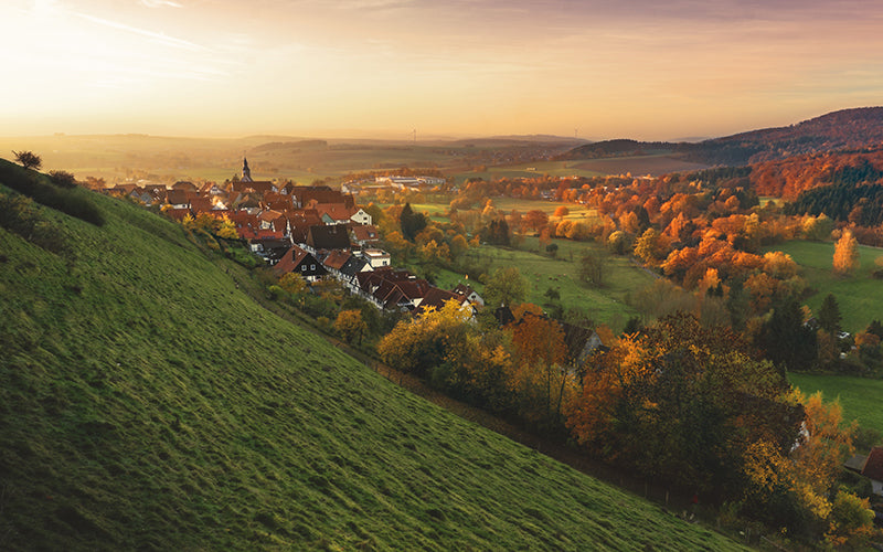 Une image d’un paysage d’automne et d’un village niché à flanc de colline.