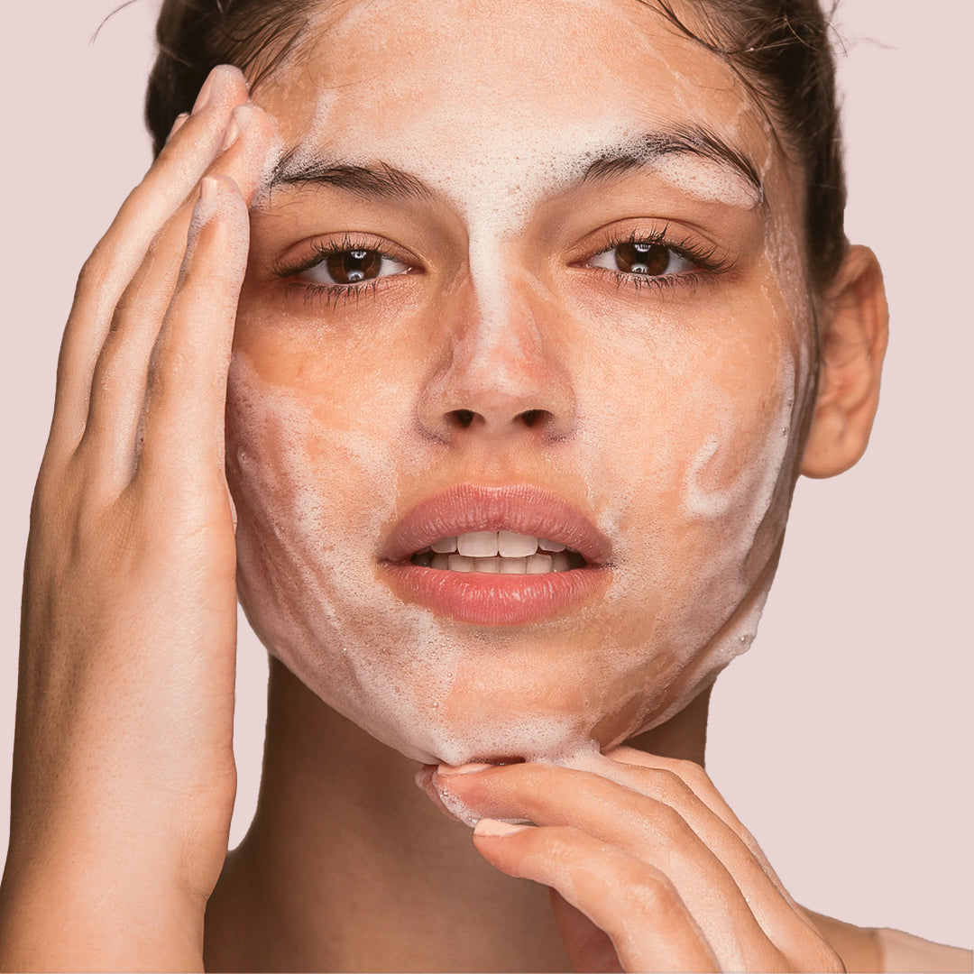 Close up of woman doing a facial with facial cleanser on her face