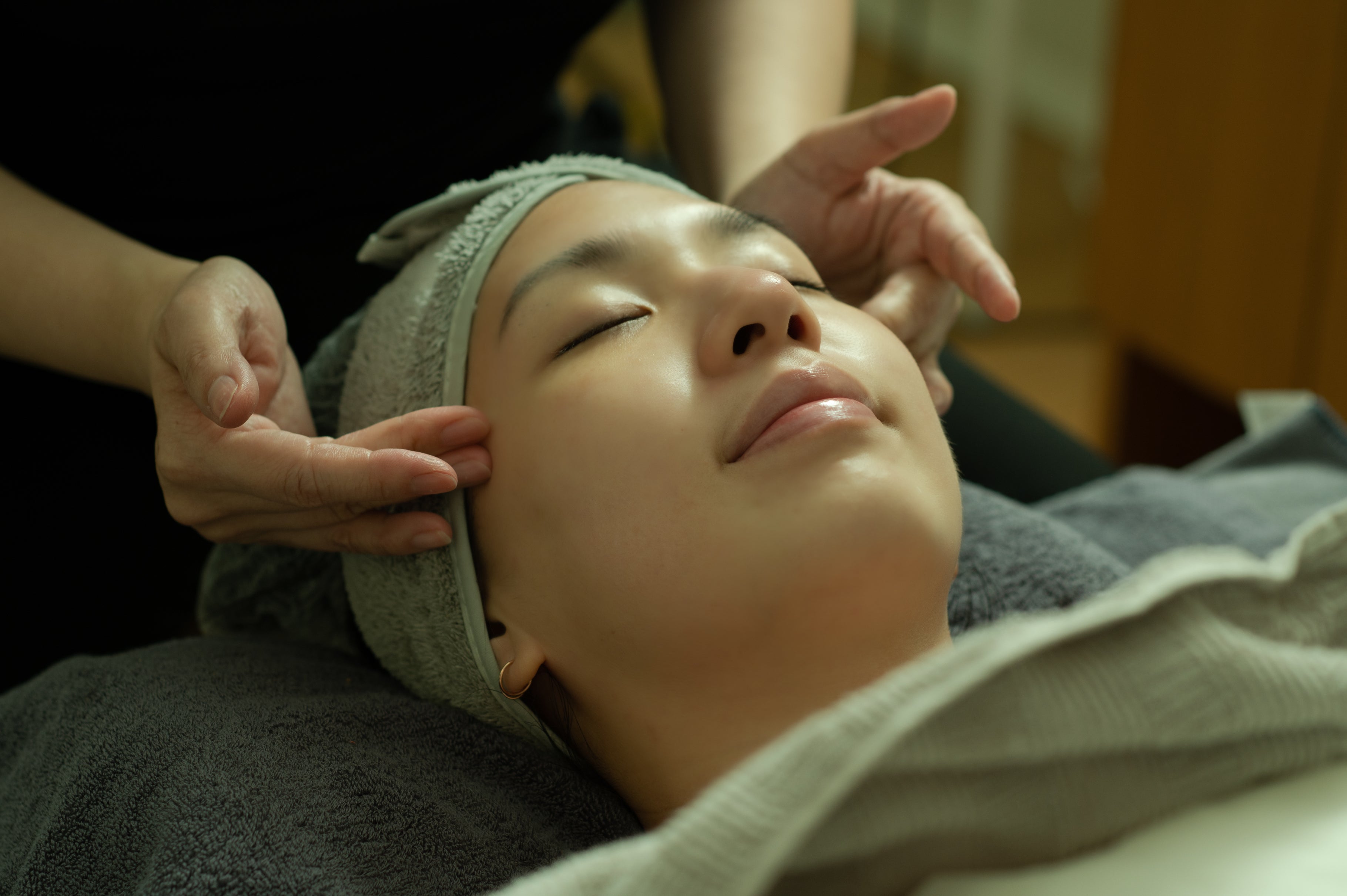 woman lying down on a bed as she gets a facial massage