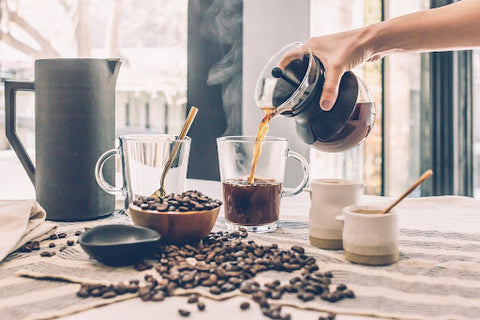Một người đang rót cà phê nóng vào một cốc nhỏ