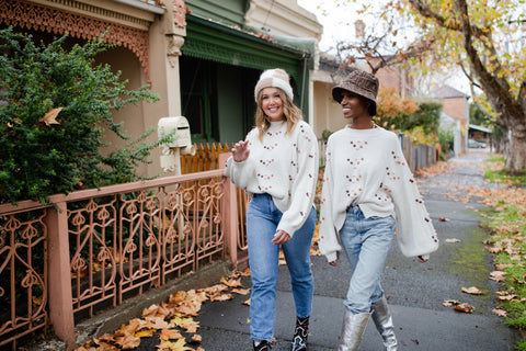 Amie Rohan and Sinead walking in an autumn leaf lined street wearing the bobble knit sweater in snow marle