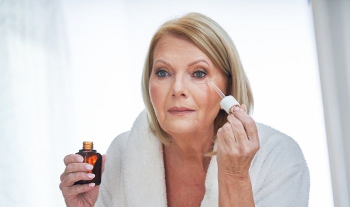 Woman applying face Anti-Aging Peptide Serum on her face.