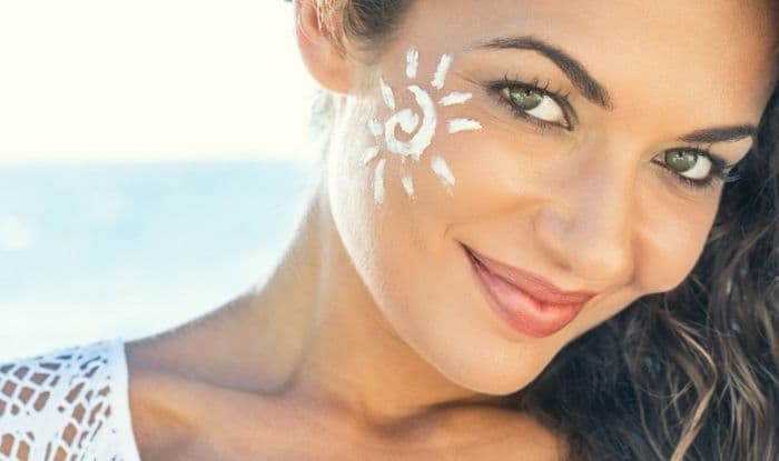 Young woman with sunscreen on face at beach