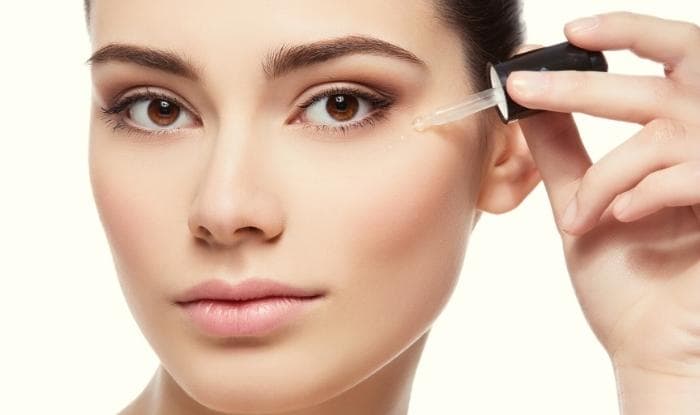 Woman applying serum moisturizer under eye area.