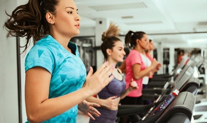 Women running  on treadmills in gym.