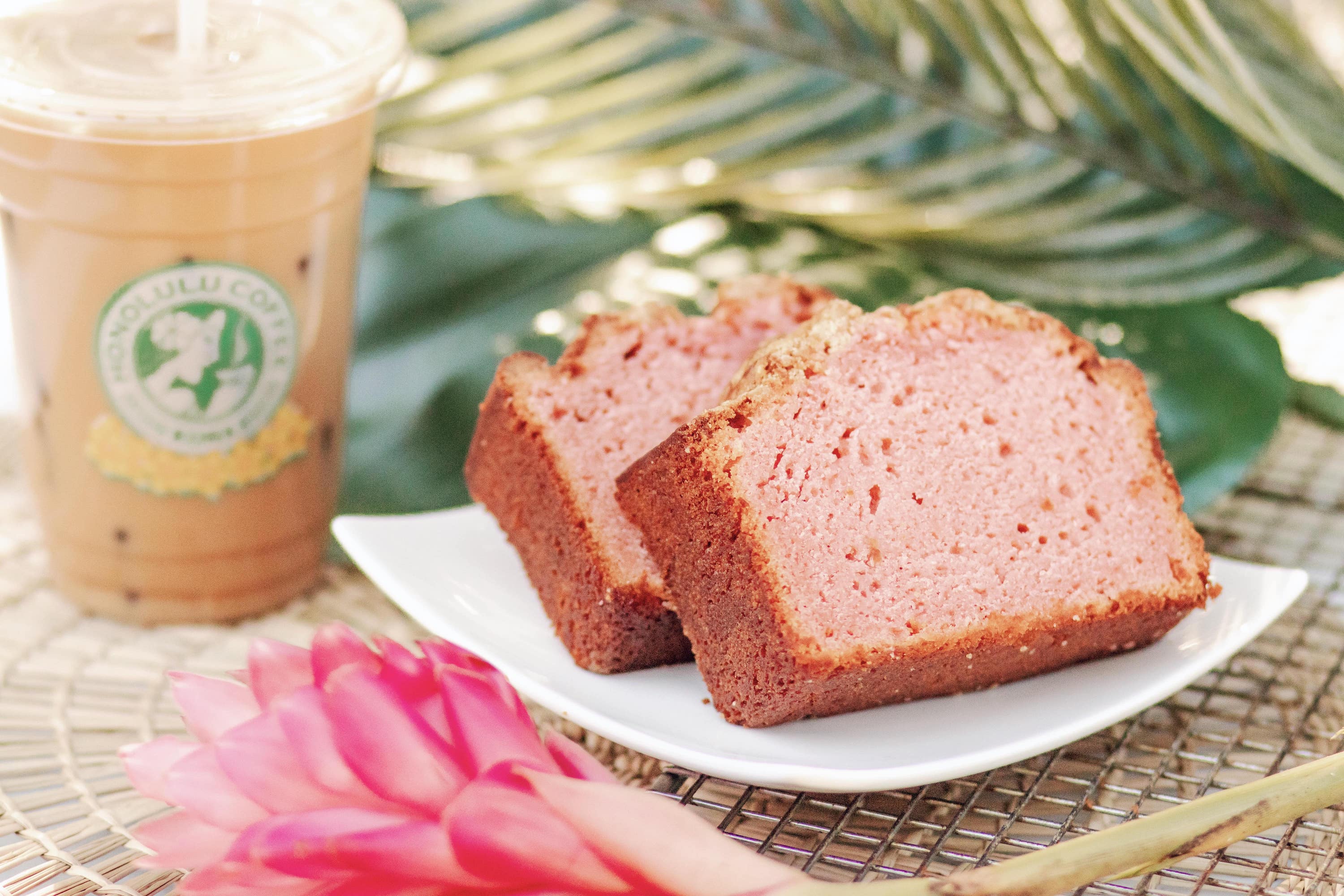 Slices of Guava Bread next to tropical flowers and an iced latte