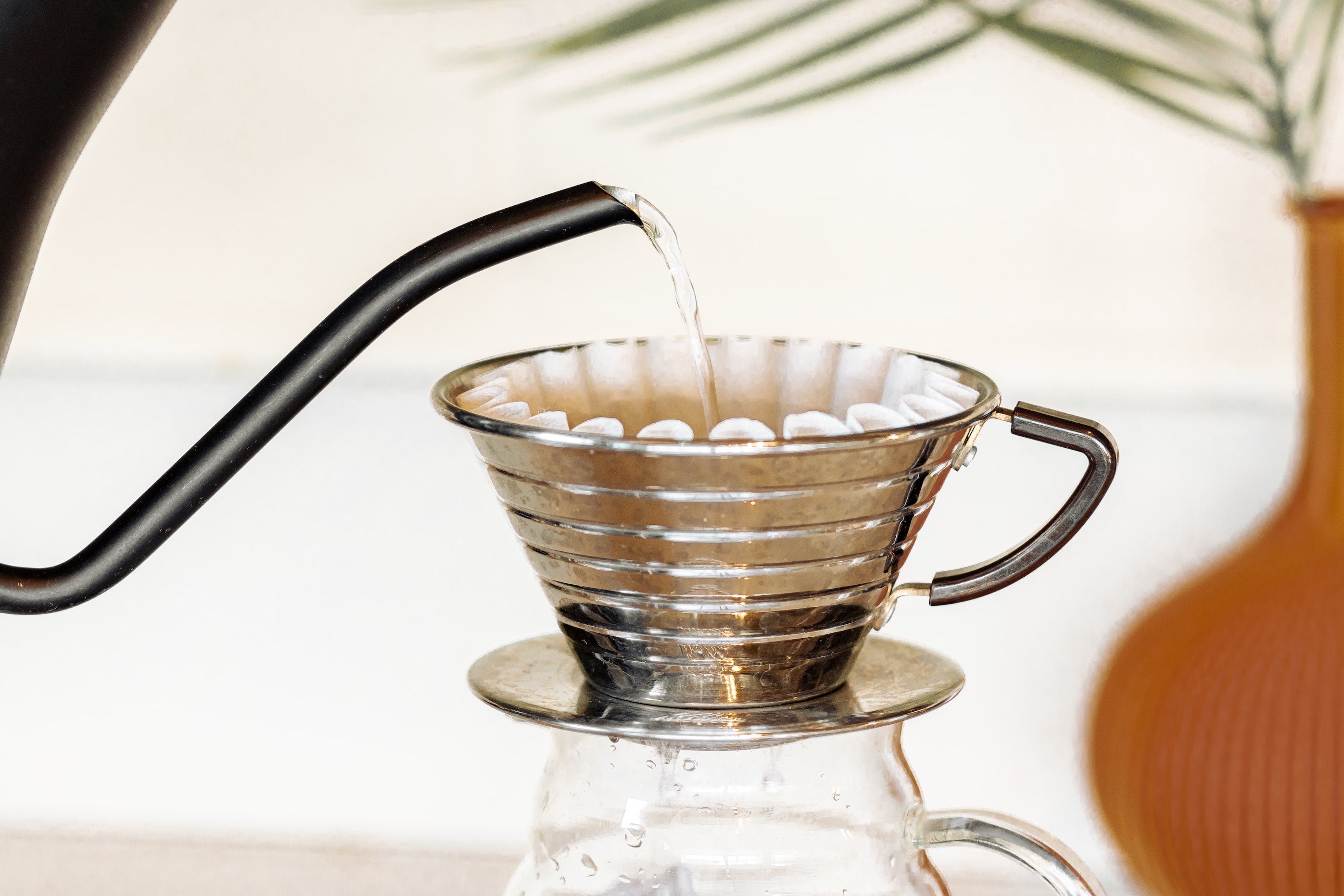 Pouring hot water to rinse and preheat a Kalita brewer and filter