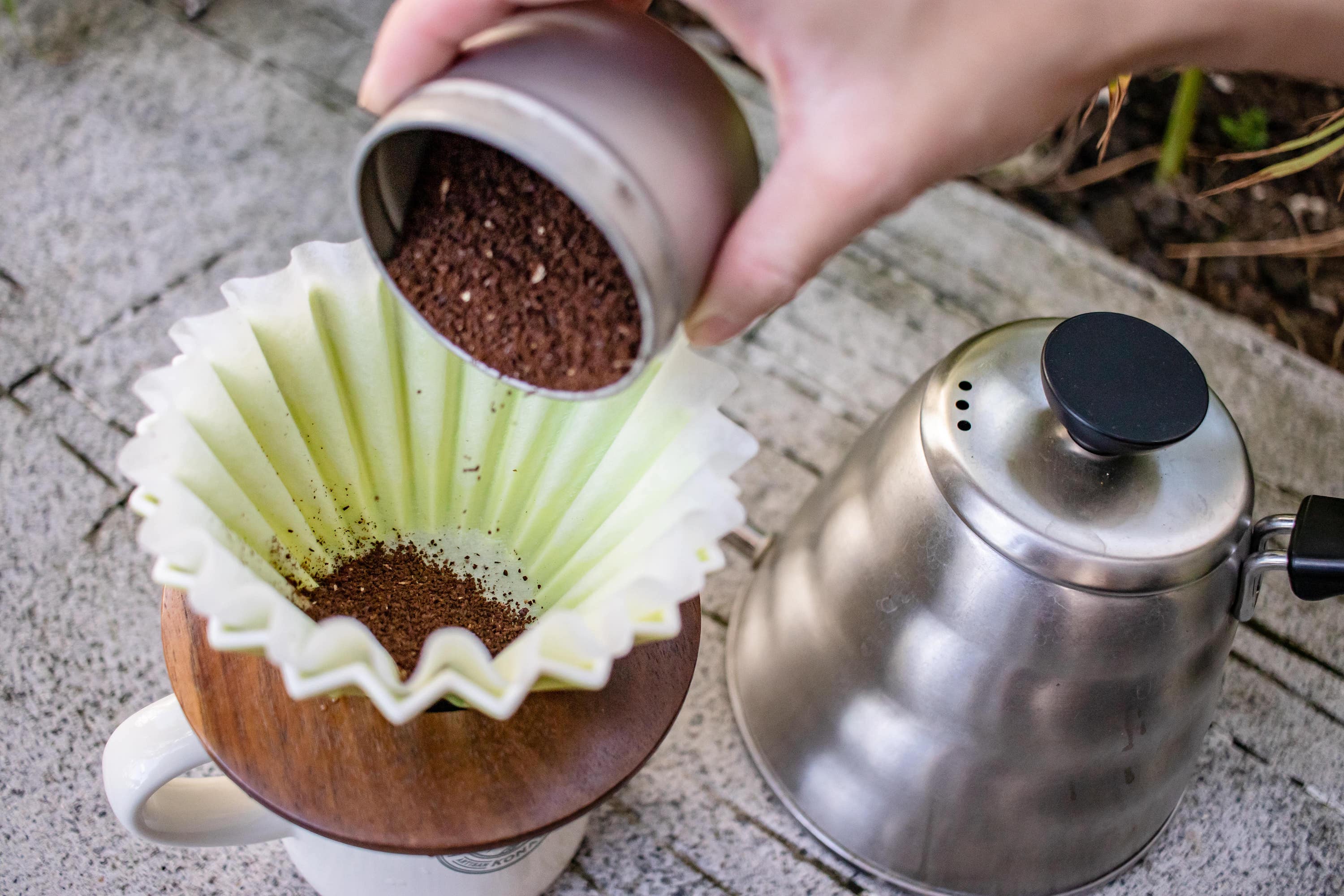 Pouring ground Kona coffee into the Origami Dripper brewer.