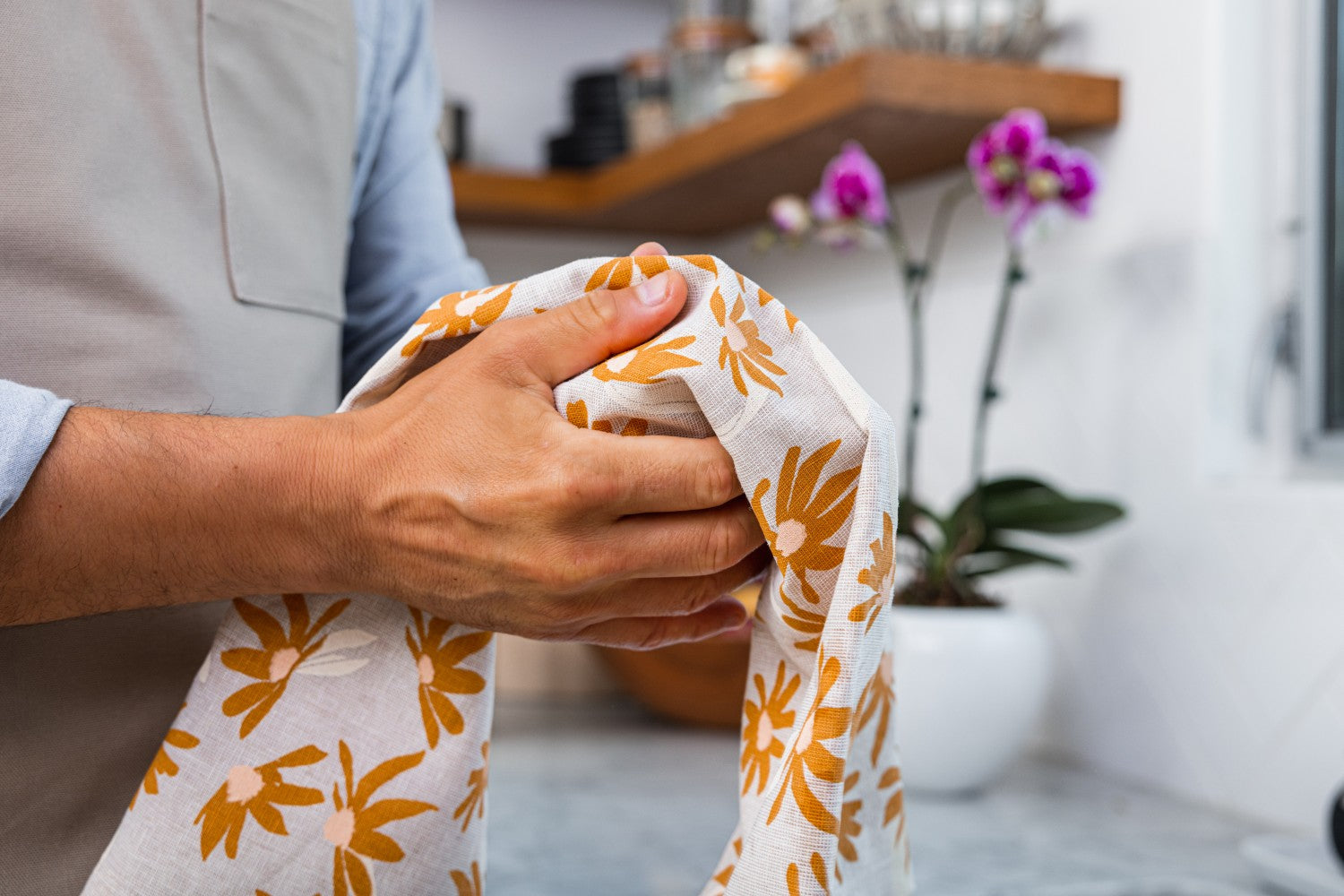 Person drying their hands with a beige towel with an orange flower pattern