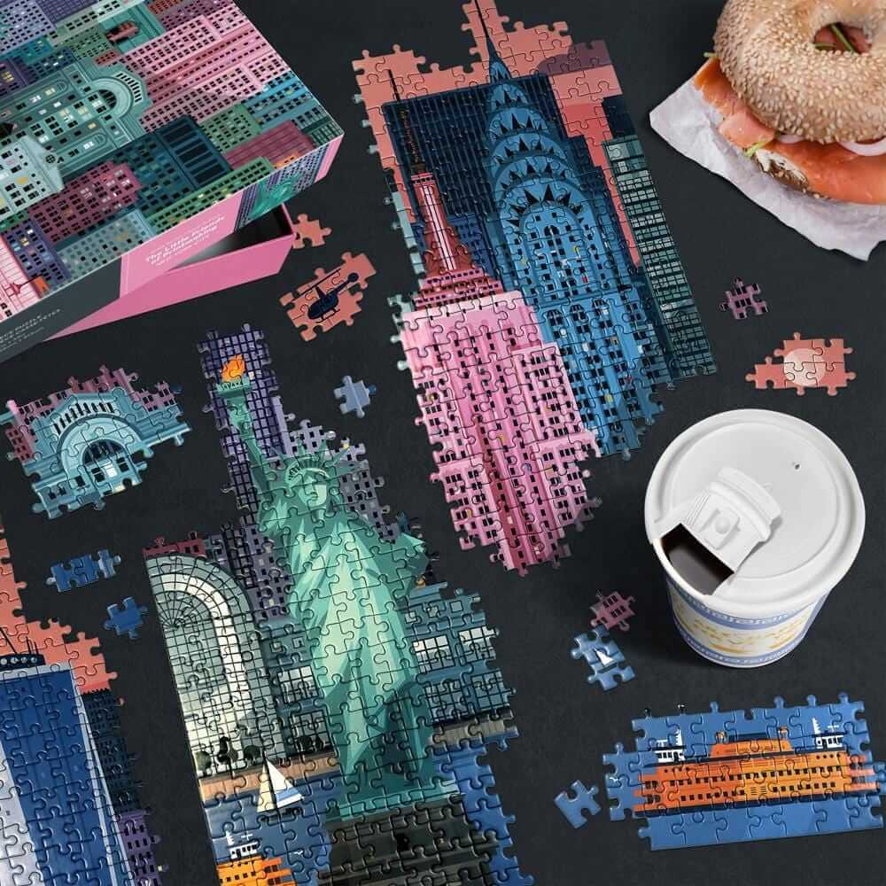 New York puzzle, coffee, and bagel on table
