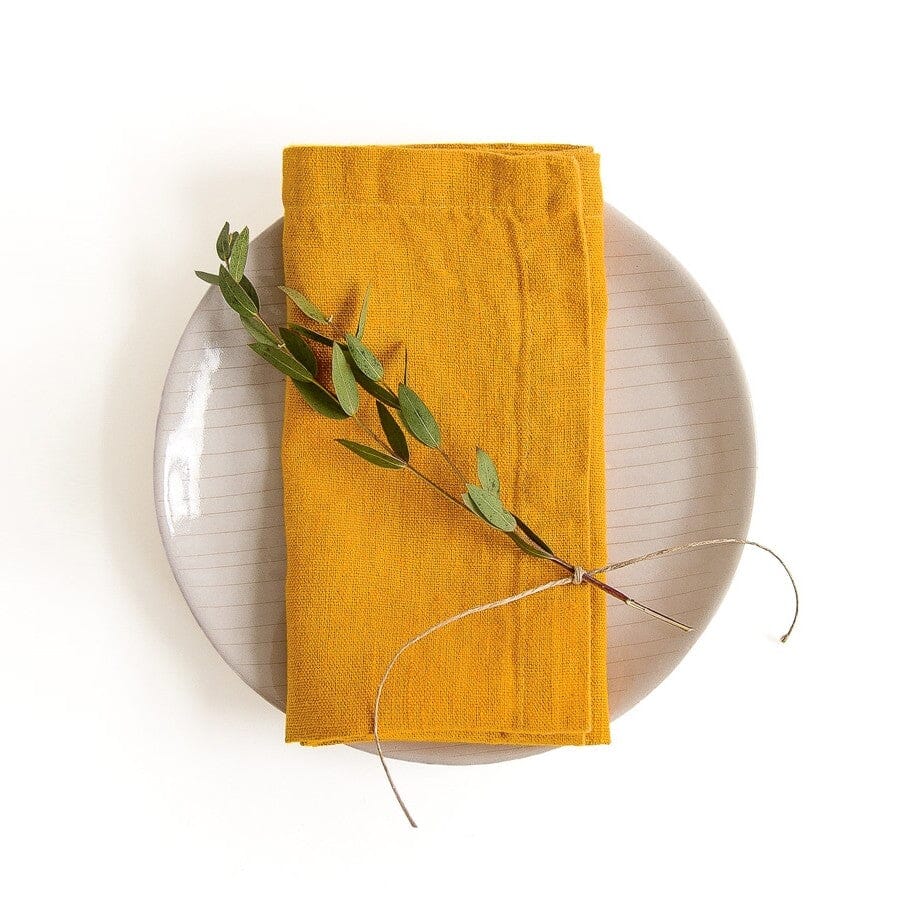 Yellow linen napkin on white plate with sprig