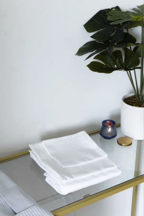 Bathroom towels on a glass table with plant