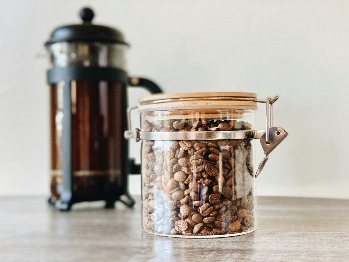 Jar of coffee beans and a coffee press in the background