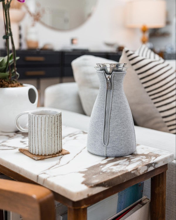 Coffee mug and carafe sit on living room table