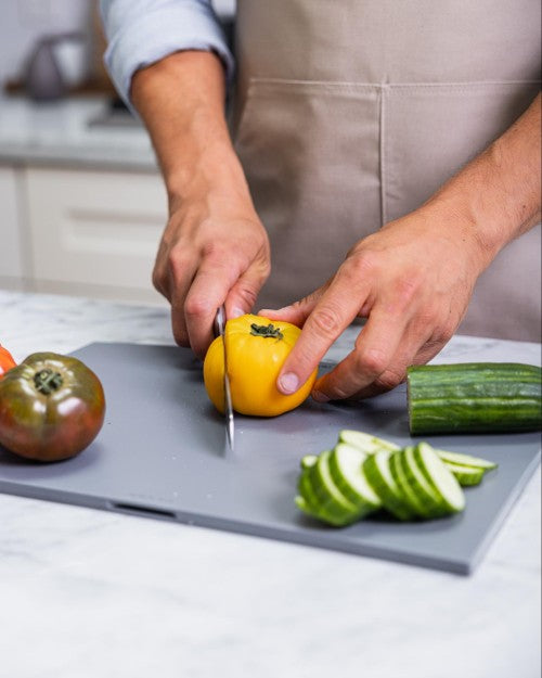 Person cutting yellow tomato on cutting board