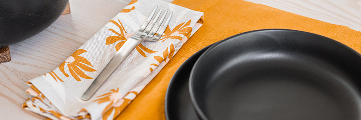 Close up of a fork at a place setting with a cream and orange napkin