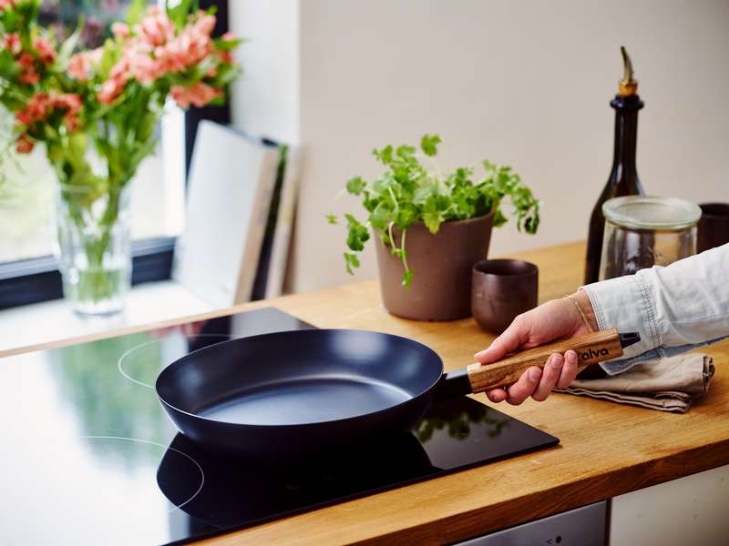 Person using a frying pan on glass stove top