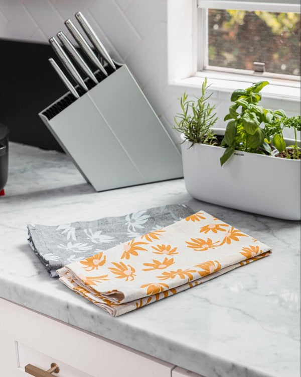 Two hand towels sit on counter next to knife block and herb planter