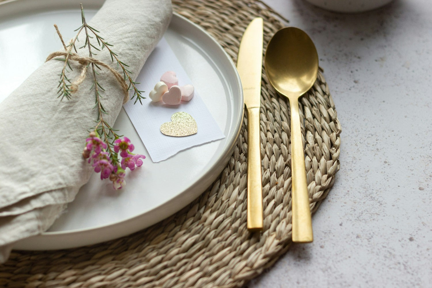 Modern valentines day dinner setting with candy hearts, flowers and gold flatware