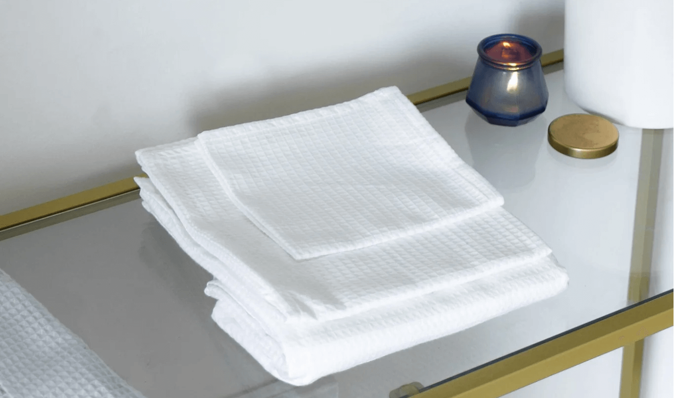 Folded organic cotton bath towels on table with candle