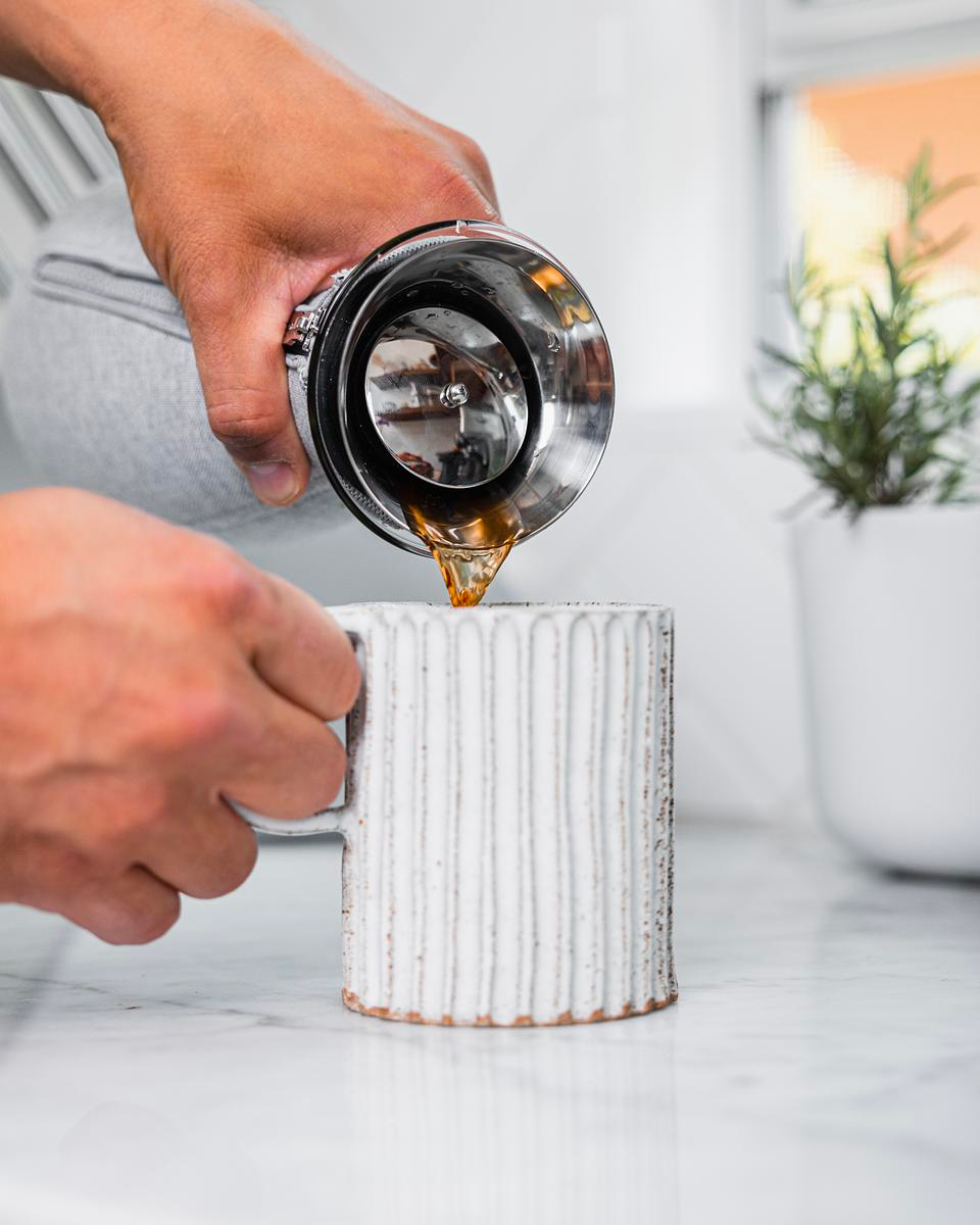 Person pouring coffee into ceramic white mug