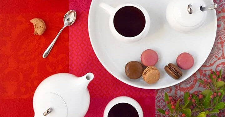 Tea set sits on table with macarons and spoon
