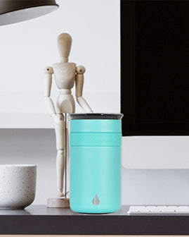 Teal mug on desk next to model