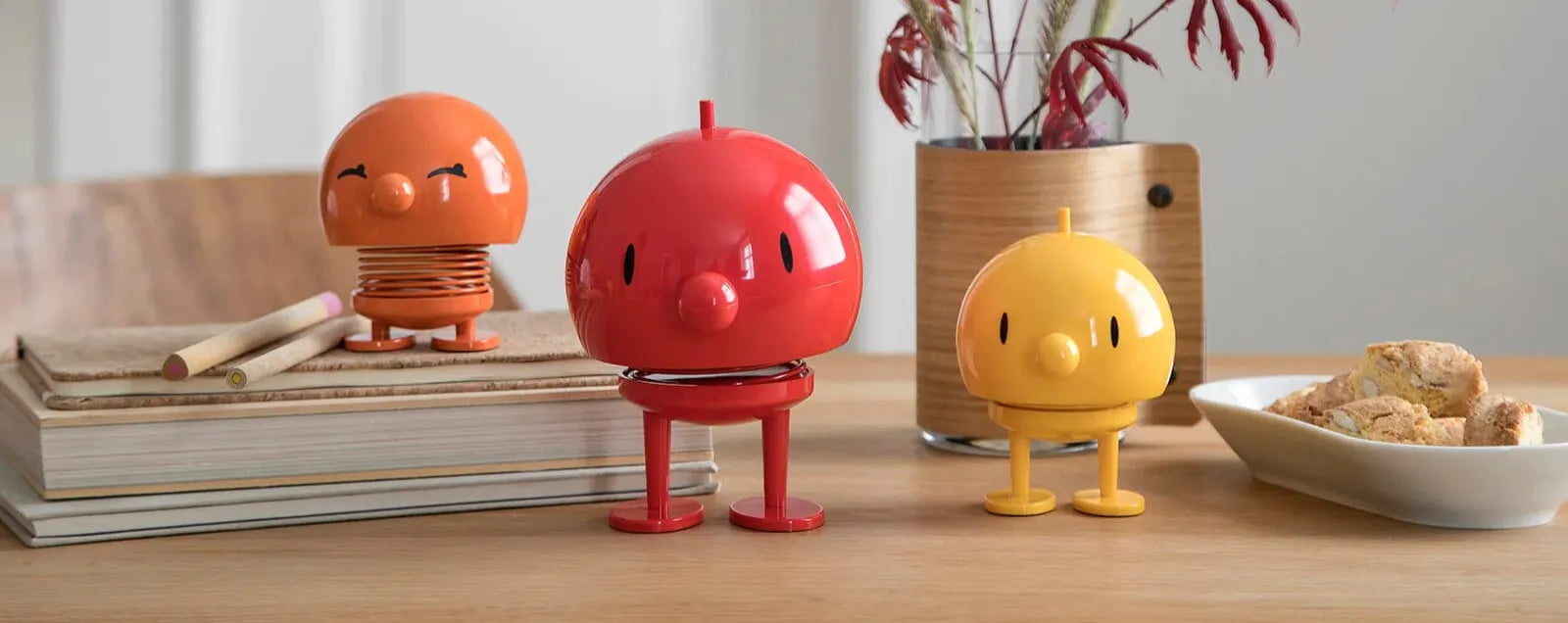 Three Hoptimist desk trinkets on a table with books