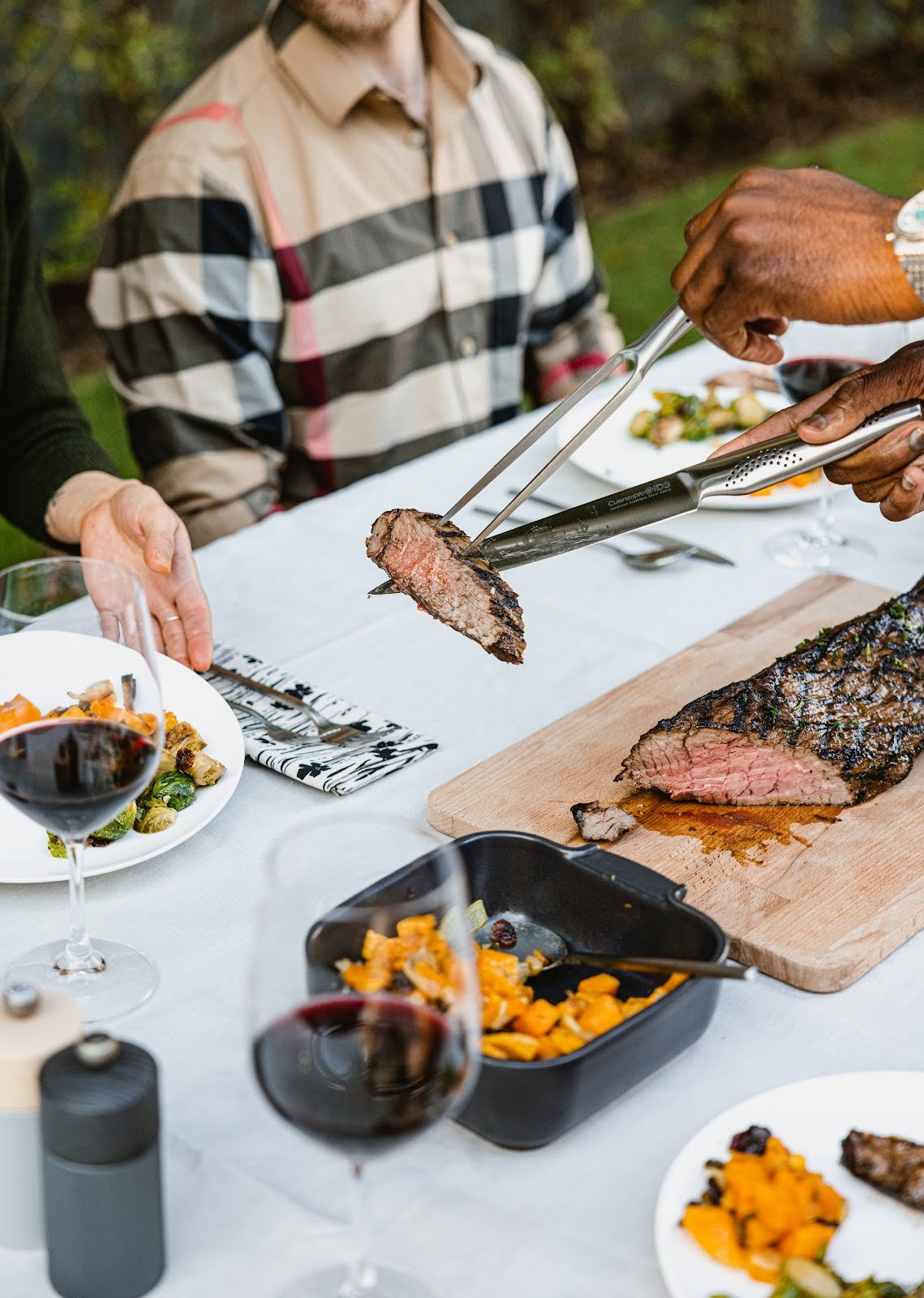 Person using a carving set to serve a roast at a dinner Table