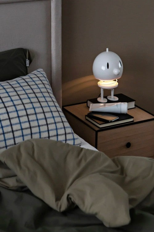 White bobble head lamp on table next to bed