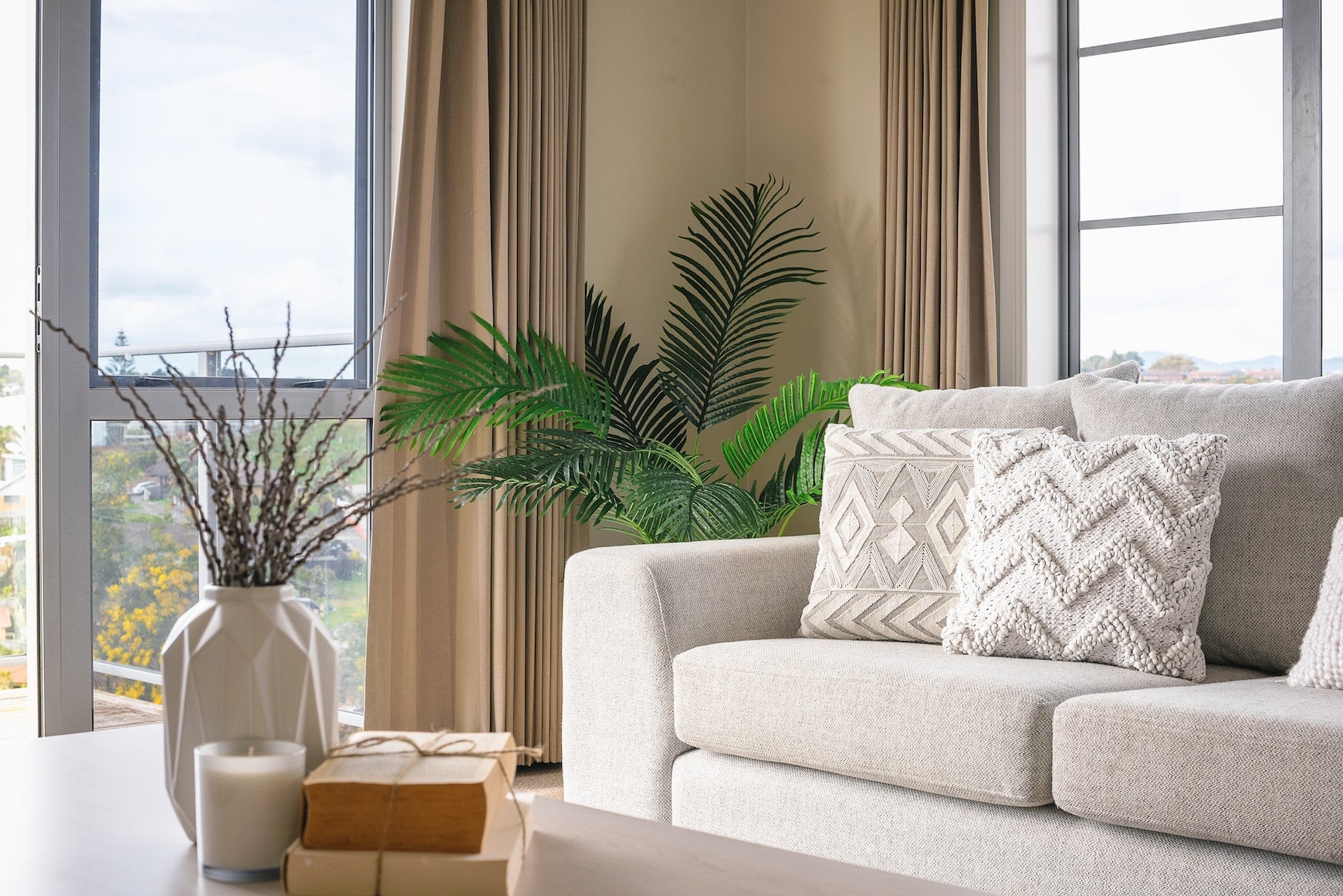 white decorative pillows on a couch next to a plant
