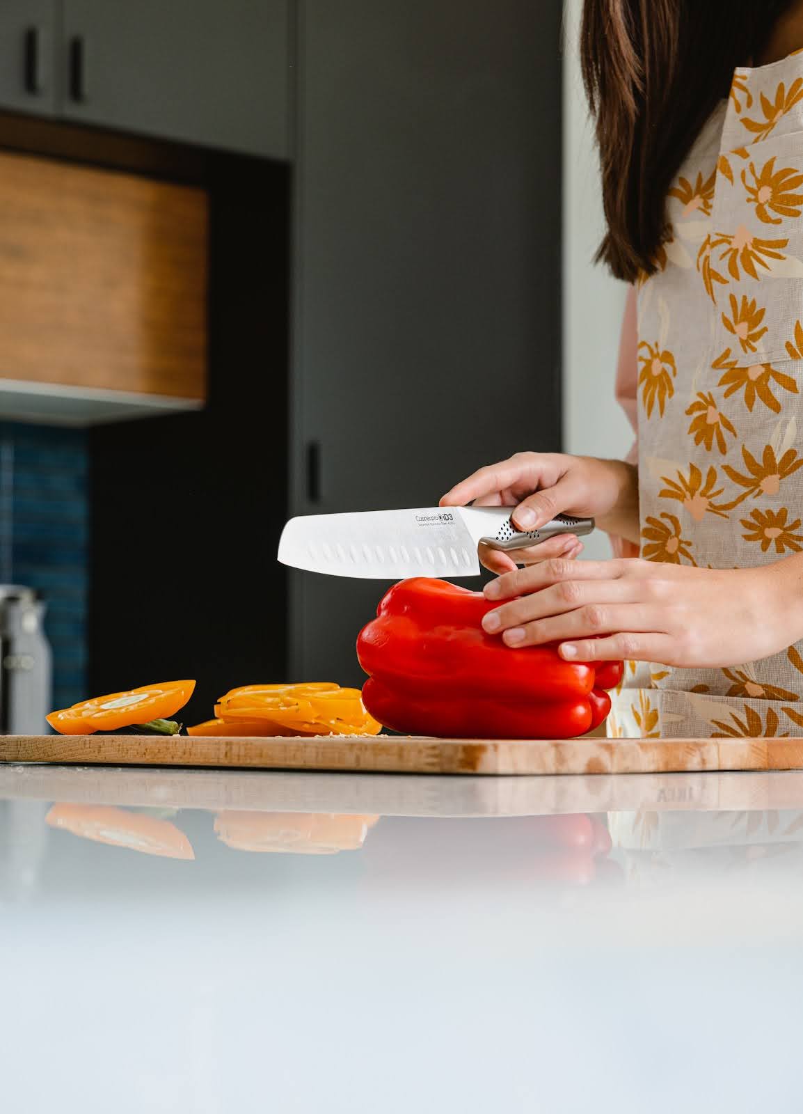 Woman in flowered apron chops peppers