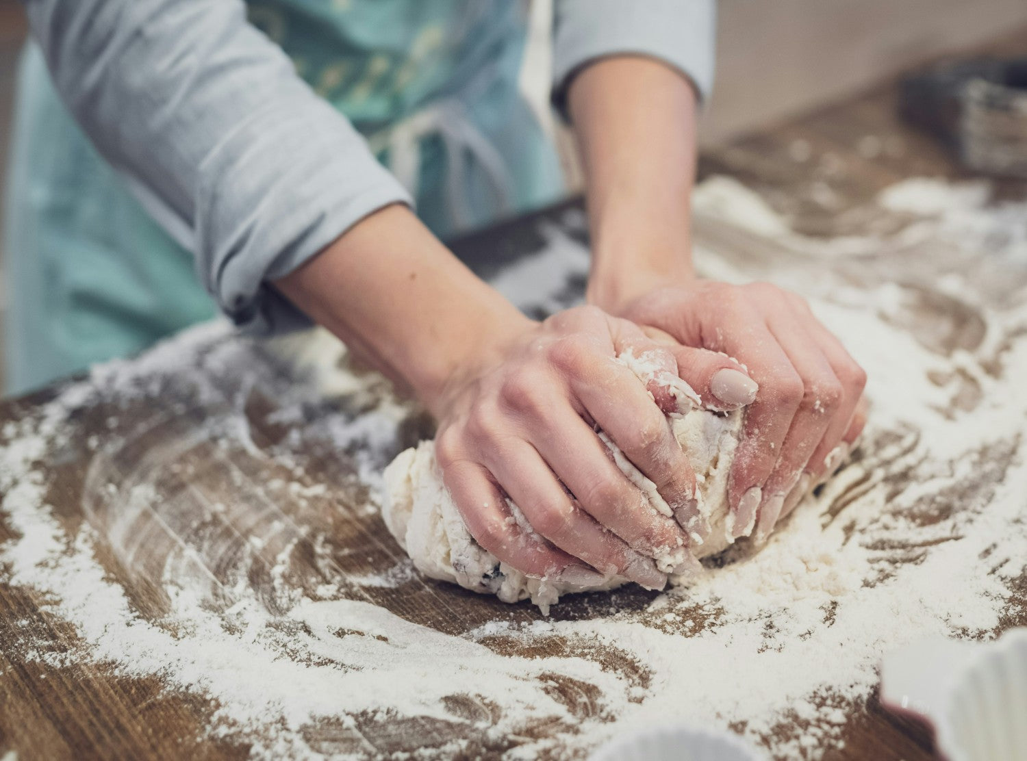 Woman kneading dough on floured table