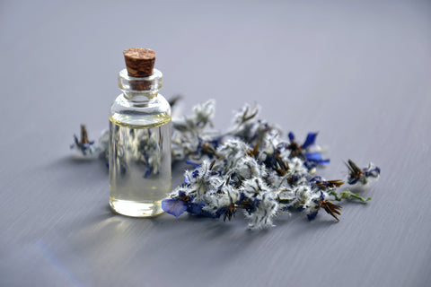 A glass bottle of essential oils and a sprig of lavender