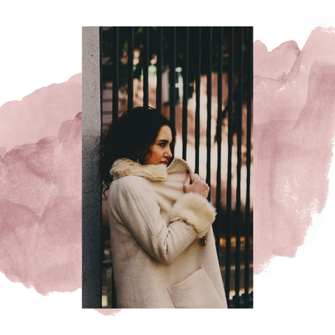 Girl wearing a fur coat (could be faux) leaning against a metal railing.