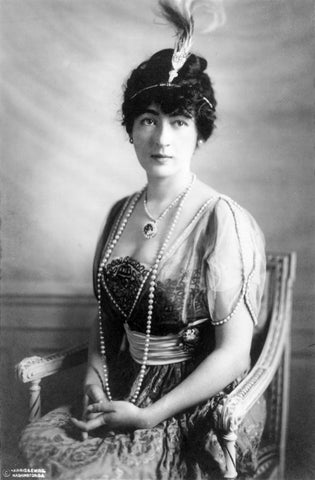 Evalyn Walsh Mclean posing on a chair wearing the Hope Diamond. The picture is in black and white.