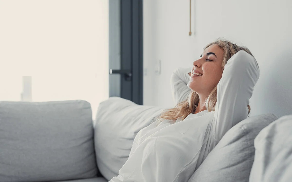 woman sat on sofa smiling after taking probiotics