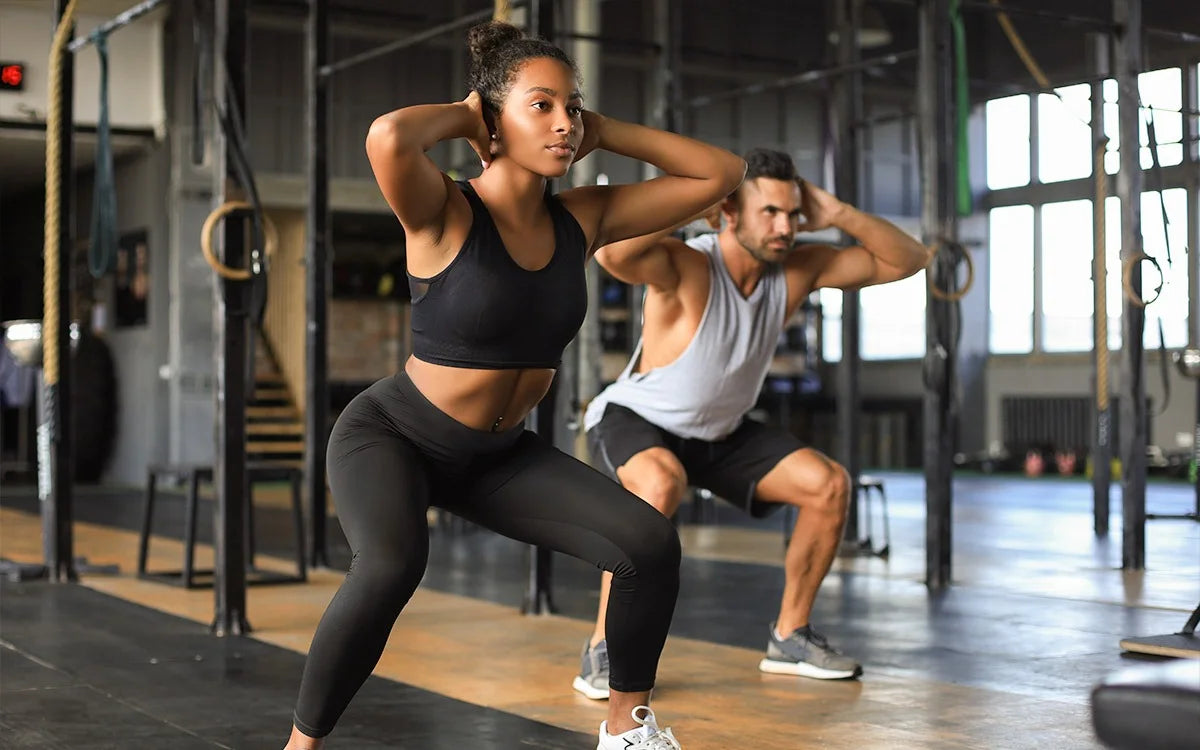 Man And Woman Performing Squat In Gym