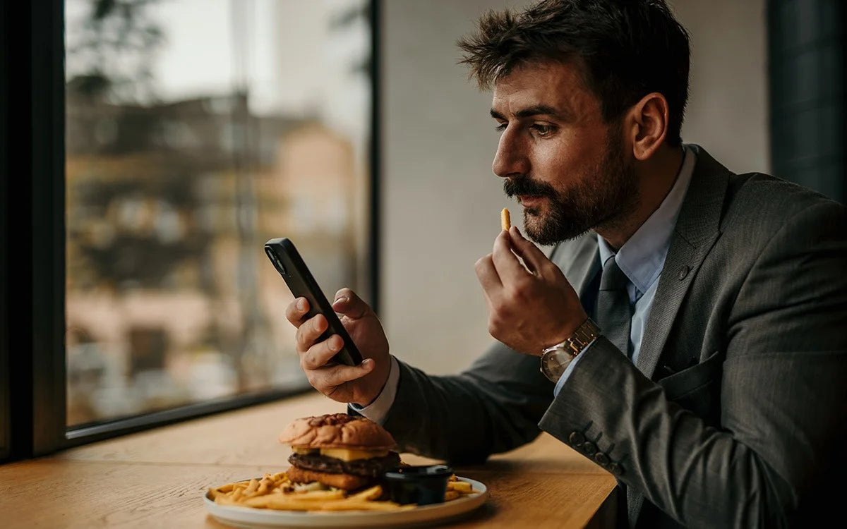Man Eating And Looking At Cellphone