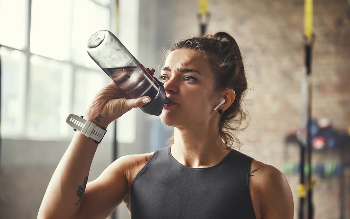 Woman drinking pre-workout in the gym