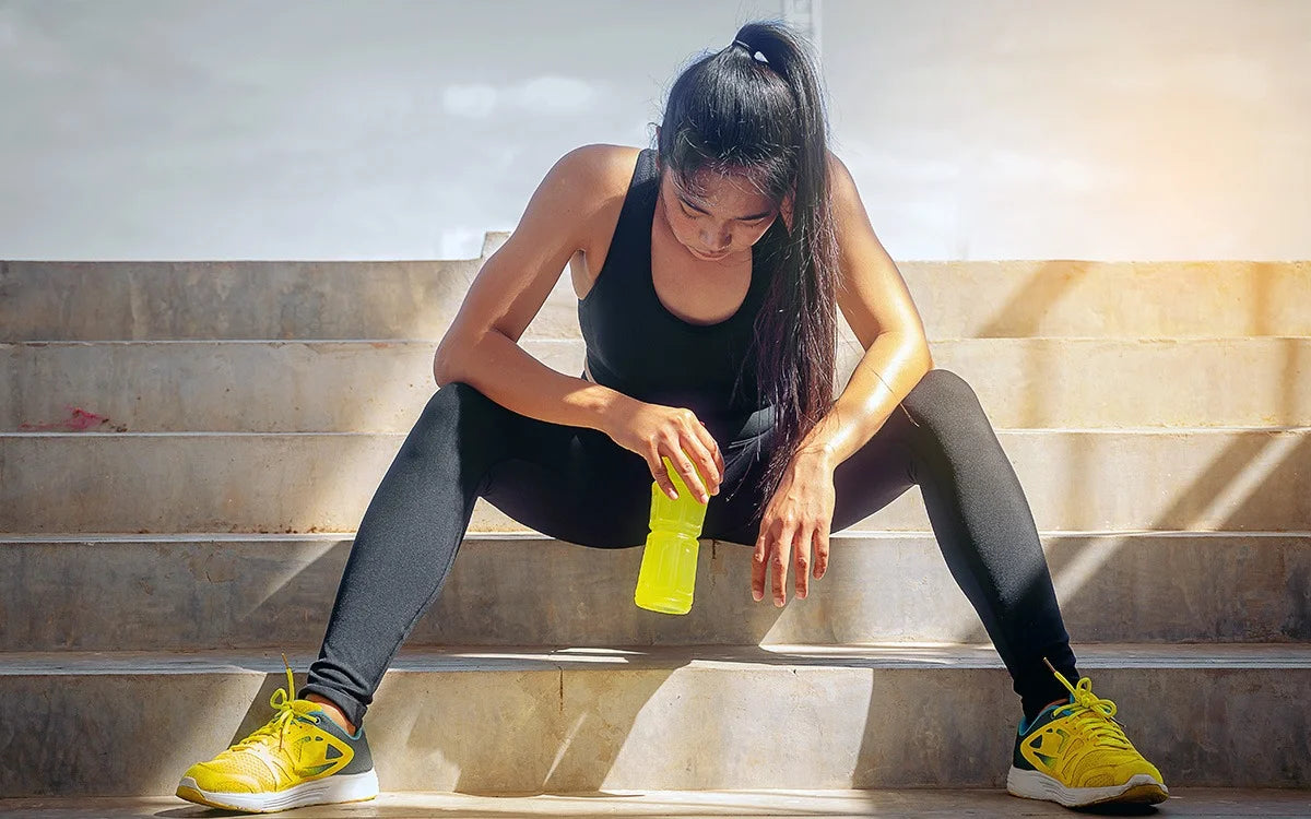 woman sat drinking electrolytes after heavy workout