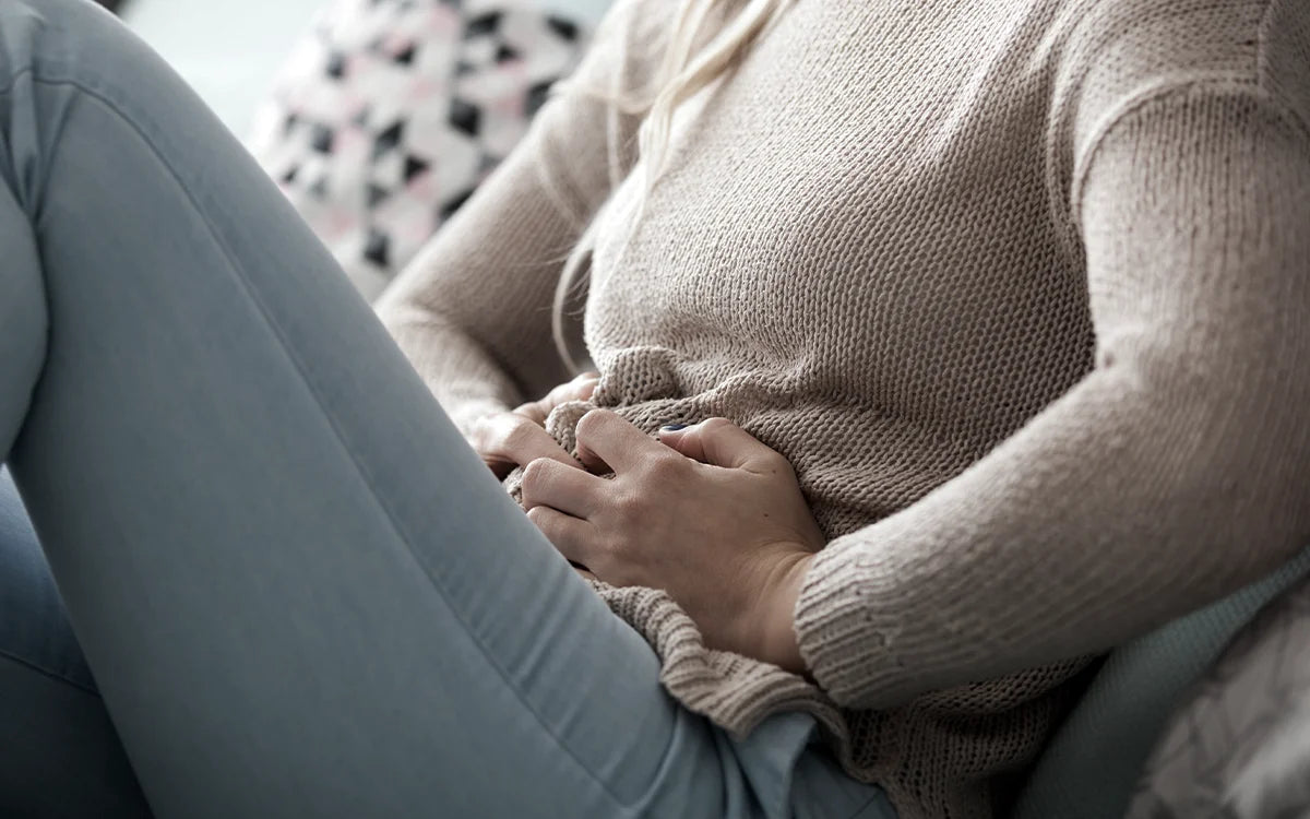 Woman sitting on couch with stomach ache