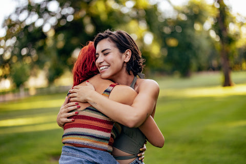 Two young women hugging each other outside in a park