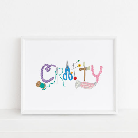 Crafty Illustrated 8x10 art print by Sunny Day Designs features colorful drawings of various sewing and craft supplies that spell out the shape of the word "CRAFTY". White background. Sold unframed. Images shows a framed art print in a white picture frame and on a white background.