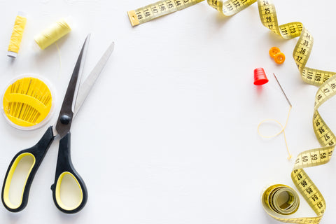 Sewing supplies, scissors, pins, and measuring tape on a white background
