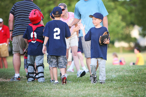 Kids and parents giving high fives after a baseball little league sports game