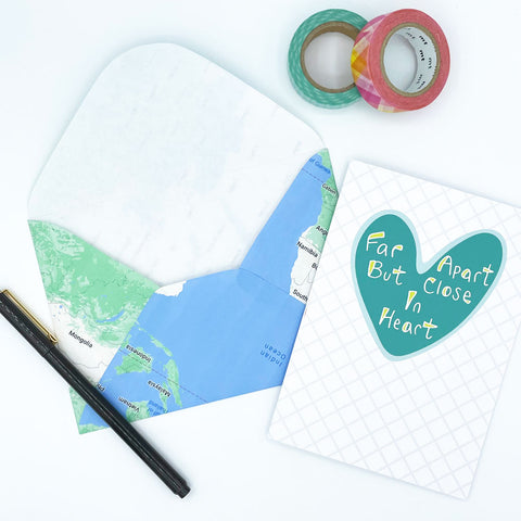 Blue and Green Mailing Envelope Made From a Repurposed Map next to Colorful Washi Tape, a pen, and a Far Apart Heart greeting card by Sunny Day Designs - Snail Mail Blog Post