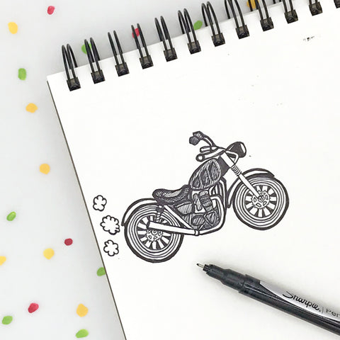 Sharpie sketch of a motorcycle in a ring bound sketchbook with confetti in the background by Shelley Schmidt of Sunny Day Designs